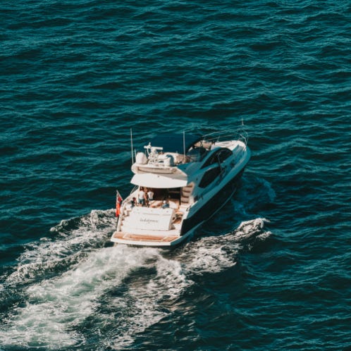 Modern big black crane and wheels on ship in bay next to settlement on mountain slope